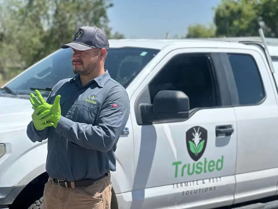 Valentin Moriel putting on nitrile gloves beside the Trusted Termite and Pest Solutions truck